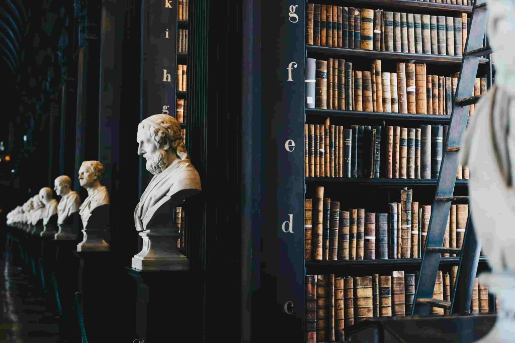 Die Bibliothek mit Büchern und Statuen einer Kanzlei, welche dabei unterstützt, Scheinselbständigkeit zu vermeiden.